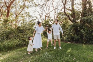 Parents swing their little boy between them as they stand in a green field