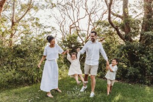 Parents swing their little girl between them as they stand in a green field