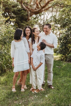 A family stand together laughing in a bushy park at sunset