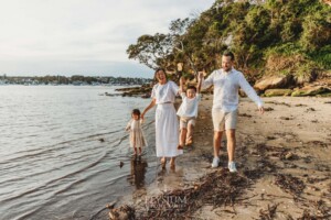 Parents swing their kids between them as they walk across the beach sand