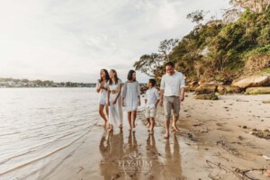 A family walk along the waters edge at sunset on the beach