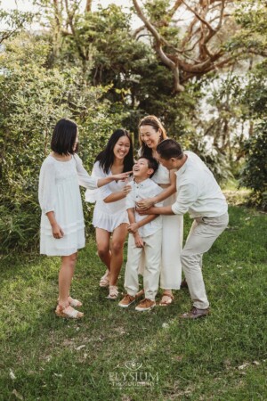 Parents tickle their children as the giggle in a green field