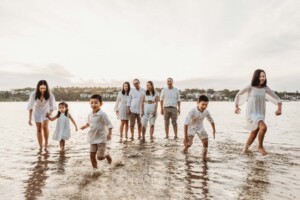 A family race through shallow water towards the shore at sunset