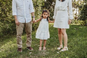 Parents hold their little girls hands as she stands between them