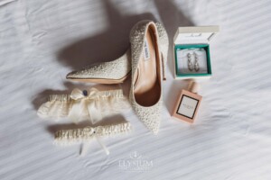 Bridal details sit on a white bed before the wedding at Burnham Grove
