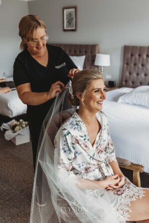 The bride sits while Iconix Bridal Salon fix her veil to her hair