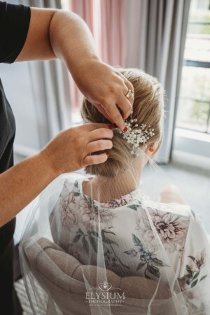 The bride sits while Iconix Bridal Salon fix her veil to her hair