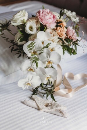 Bridal flowers sit on a white bed during the wedding prep