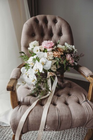 A large bridal bouquet of flowers sits on an armchair