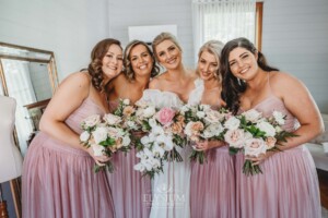 A bride stands with her bridesmaids before heading out to their wedding ceremony