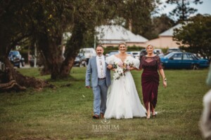 A bride walks across the lawn towards the wedding ceremony at Burnham Grove