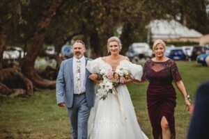 A bride walks across the lawn towards the wedding ceremony