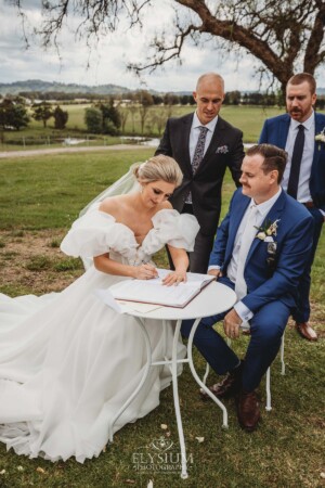 A bride and groom sign their wedding certificate during the ceremony