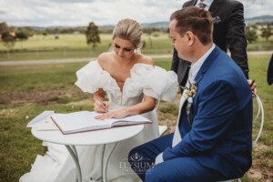 A bride and groom sign their wedding certificate during the ceremony