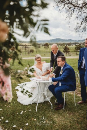 A bride and groom sign their wedding certificate during the ceremony