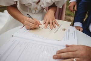 A bride signs their wedding certificate during the ceremony