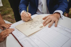 A groom signs their wedding certificate during the ceremony