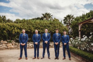 Groomsmen stand in the driveway of their Camden wedding venue