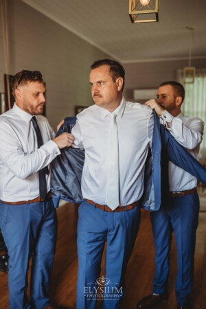 Groomsmen help the groom get dressed before the wedding