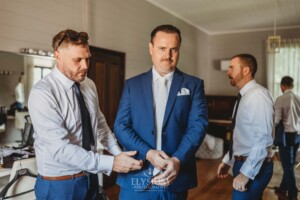 Groomsmen help the groom get dressed before the wedding