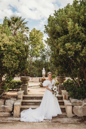 A bride stands on stone steps in front of the Burnham Grove fountain