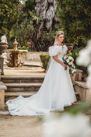 A bride stands on stone steps in front of the Burnham Grove fountain