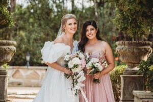 Bridal party pose for photos in front of green hedges