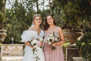 Bridal party pose for photos in front of green hedges