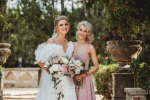 Bridal party pose for photos in front of green hedges