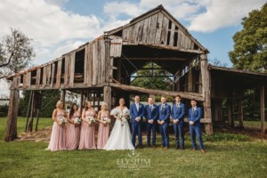 The bridal party posing for portraits in front of a rustic barn