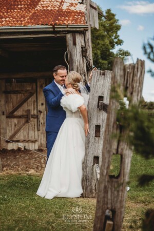 The bride and groom posing for portraits in front of a rustic barn