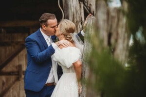 The bride and groom kiss for portraits in front the Burnham Grove barn