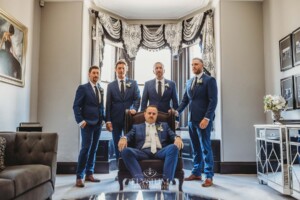 Groomsmen stand in the homestead at Burnham Grove