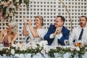 A bride and groom applaud the speeches during the wedding reception