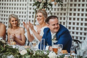 A couple claps the speeches during their wedding reception