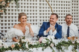 A bride and groom clap and laugh during the wedding speeches