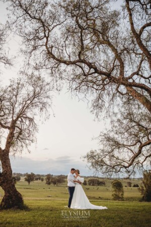 A couple stand beneath the Burnham Grove peppertrees after their wedding ceremony