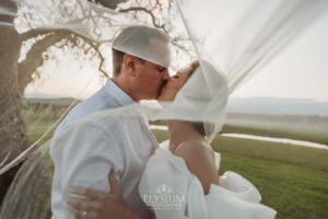 A couple kiss as the brides wedding veil sweeps around them