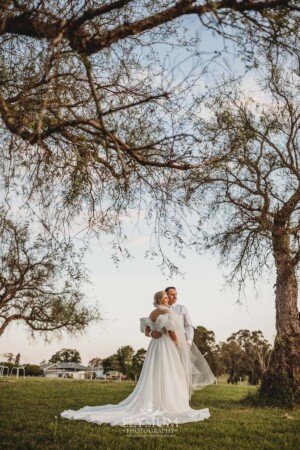 A couple stand beneath the Burnham Grove peppertrees after their wedding ceremony