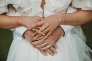 A bride and grooms hands overlap as the have wedding portraits
