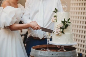 A knife cuts into a white wedding cake during a Burnham Grove reception