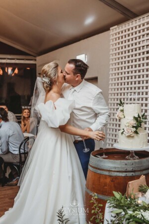 A bride and groom kiss after cutting their wedding cake during the reception