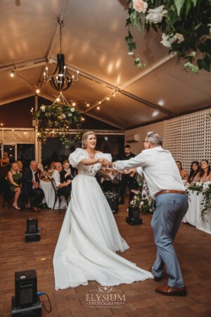 A bride shares a first dance with her father during the wedding reception