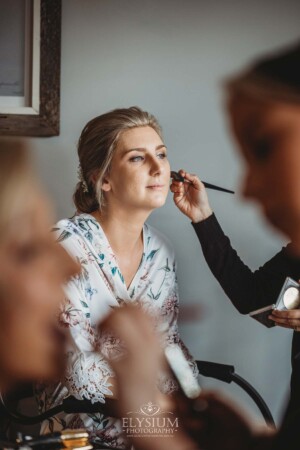 The brides sits while Iconix Bridal Salon fix her makeup before the wedding