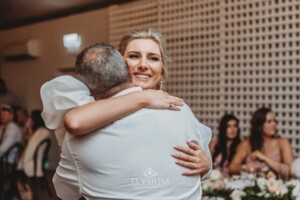 A bride hugs her father during their first dance at the wedding reception