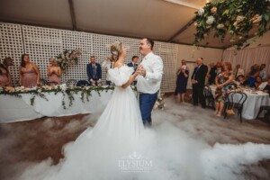 A bride and groom share their first dance surrounded by dry ice fog