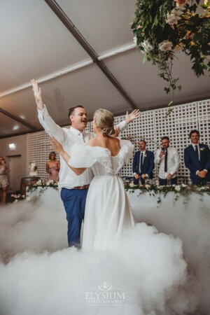 A bride and groom celebrate during their first dance surrounded by dry ice fog
