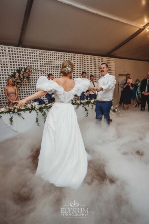 A bride and groom share their first dance surrounded by dry ice fog