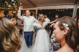 A bride and groom share their first dance surrounded by wedding guests