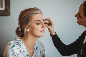 The brides sits while Iconix Bridal Salon fix her makeup before the wedding